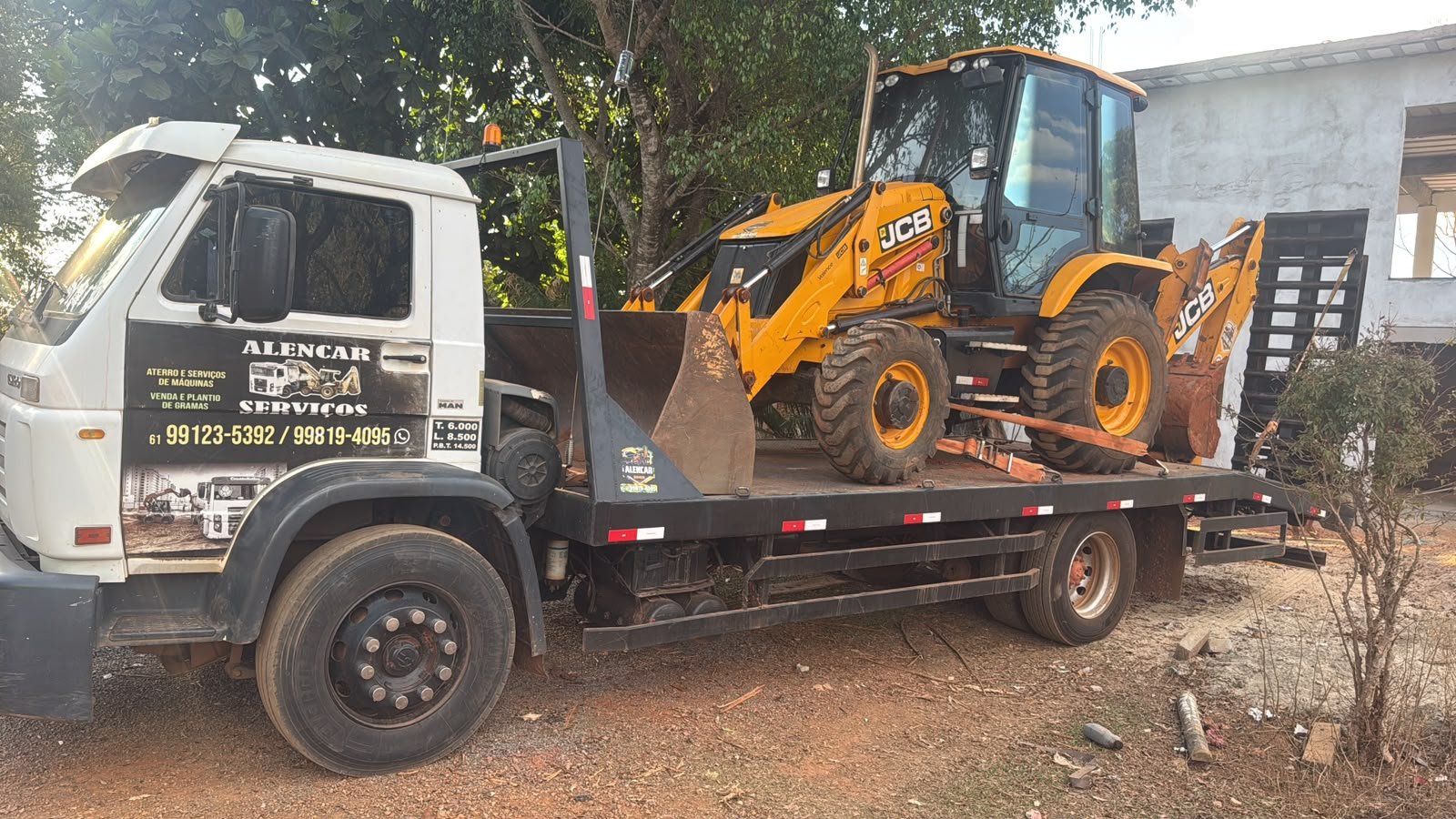 Caminhão prancha da Alencar Serviços transportando retroescavadeira JCB.